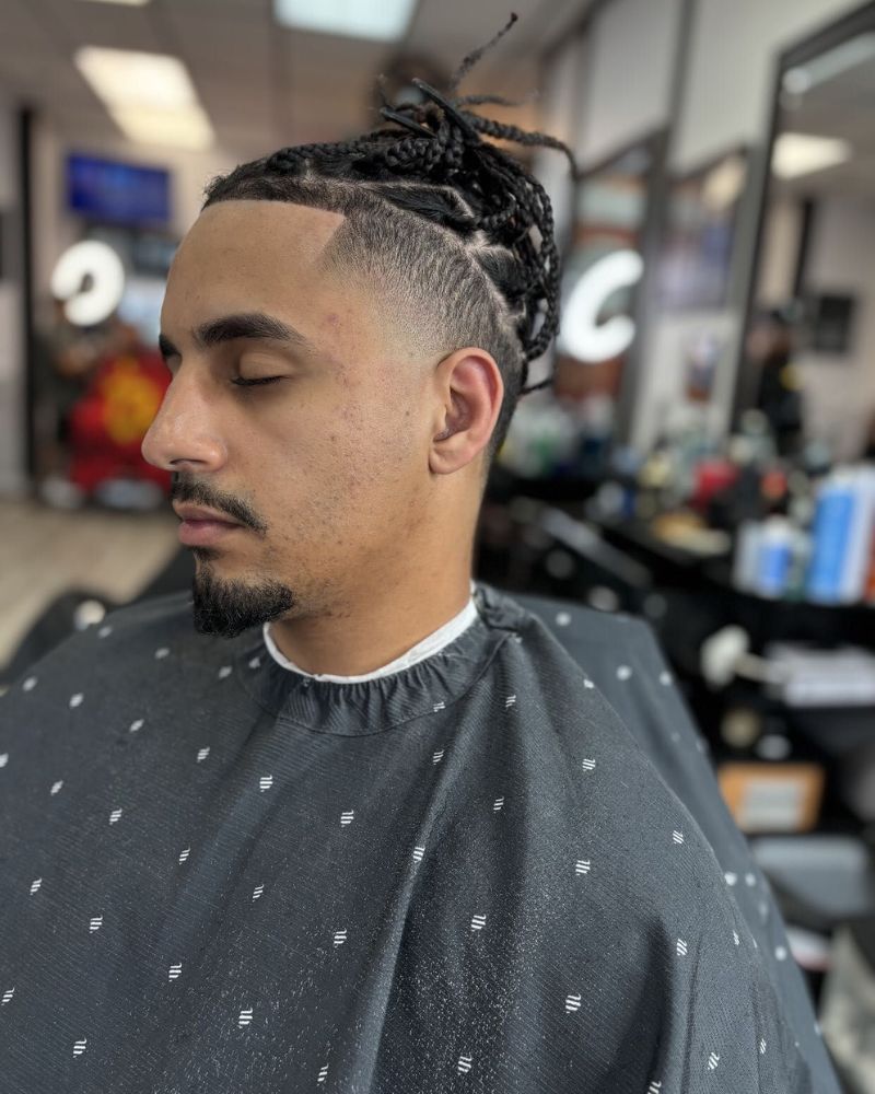 Skin fade with braids pulled up and clean beard lineup
