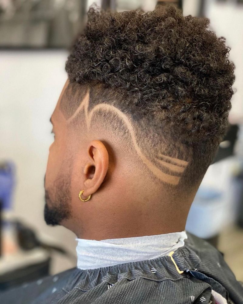 Curly top with skin fade and carved flowing design lines