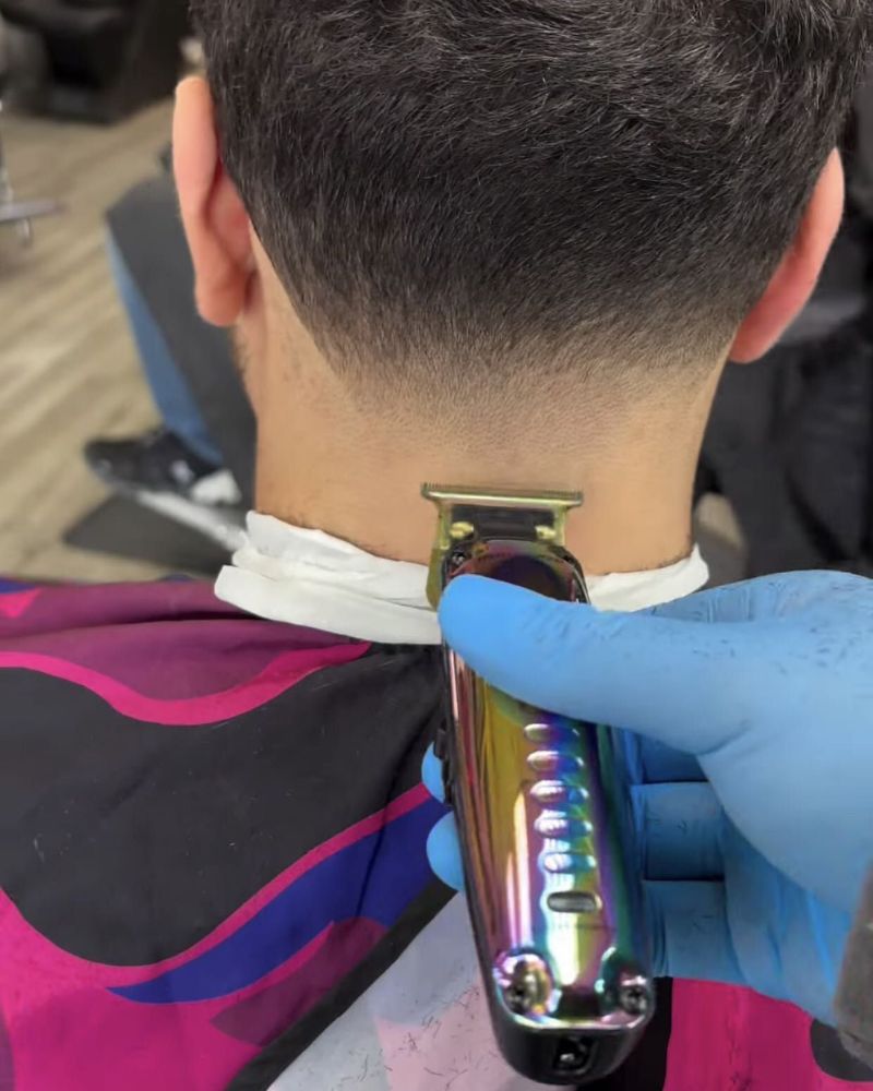 Barber finishing clean taper neckline on young client